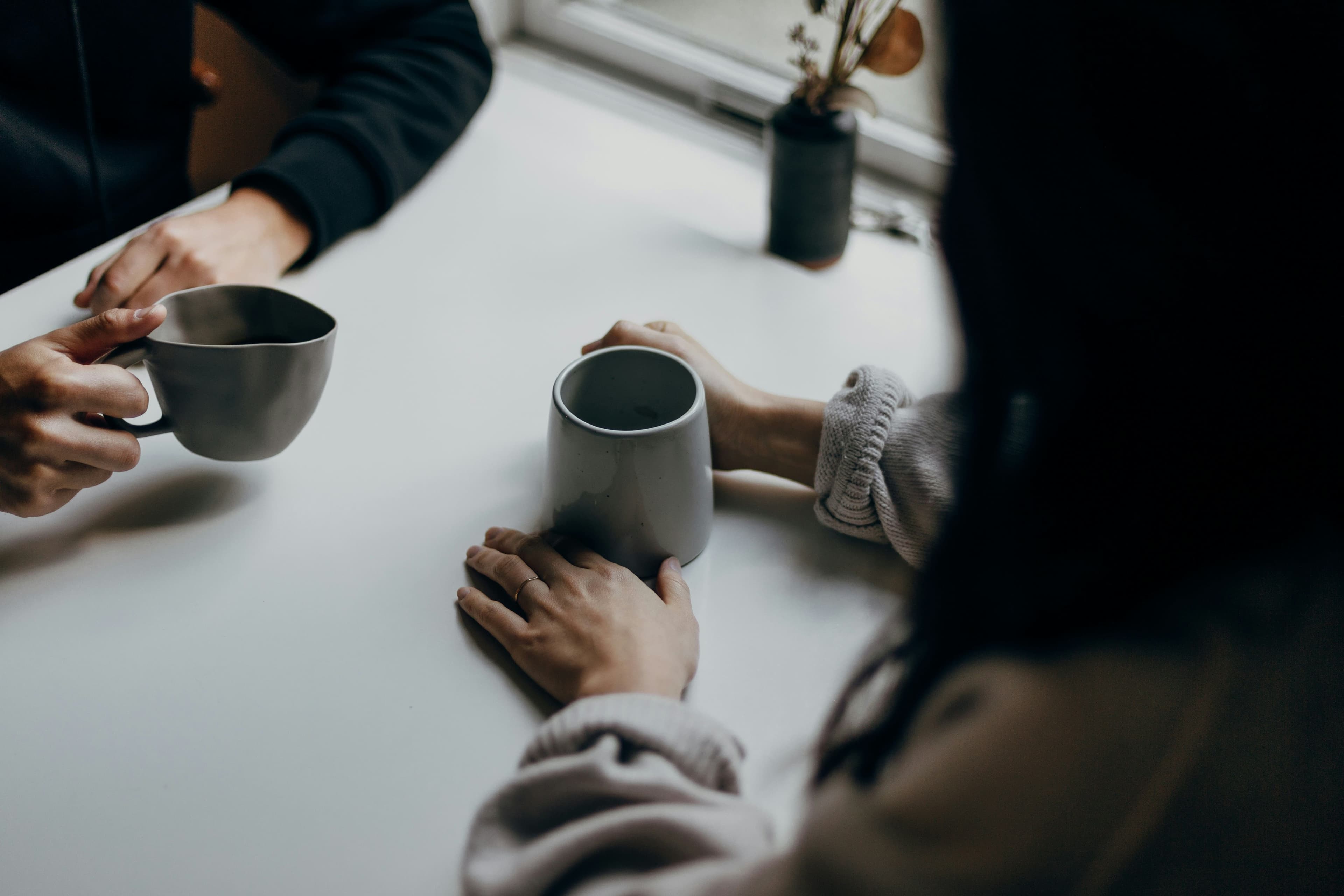 Two people during a therapy session, only the arms are visible holding ceramic mugs